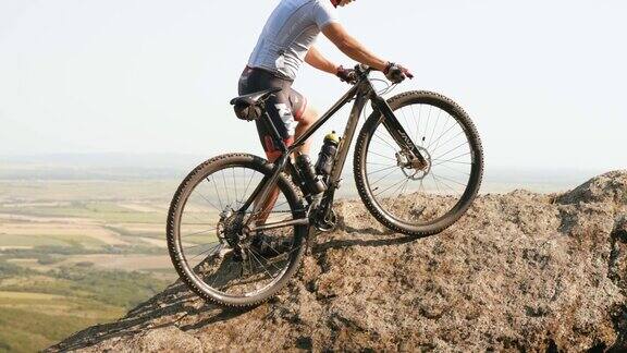 极限越野摩托车手推着他的自行车爬到岩石的顶部