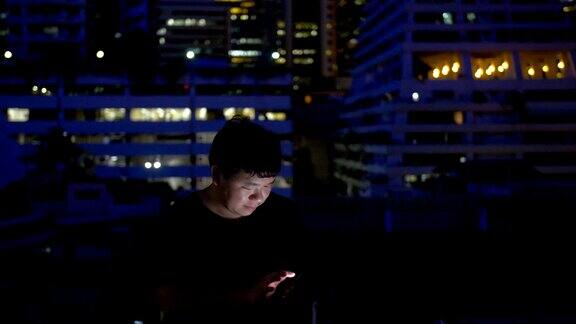 一个男人晚上在屋顶上用智能手机