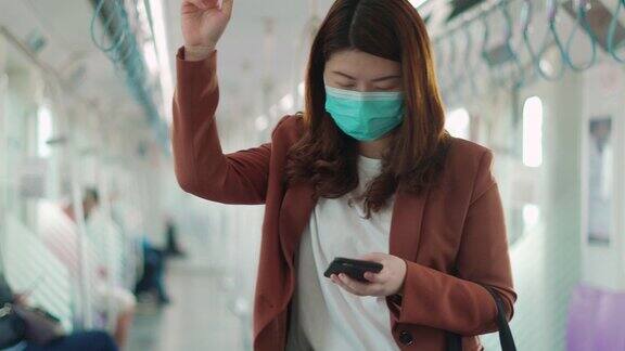 女商人坐在火车上戴着防护面具用着智能手机