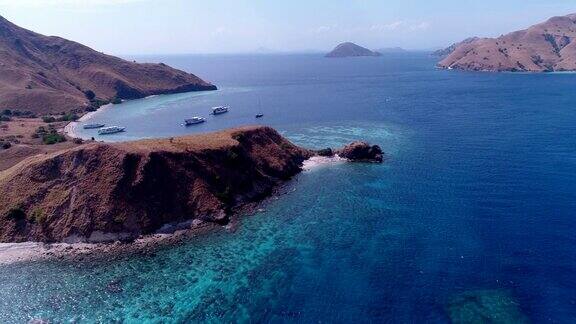 航拍干燥的岩石岛碧蓝的海水海湾里的潜水船