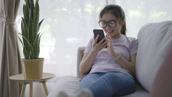 年轻女子在家里的客厅里放松使用手机