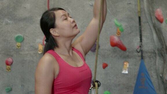 亚洲女子用绳子保护另一名攀登者