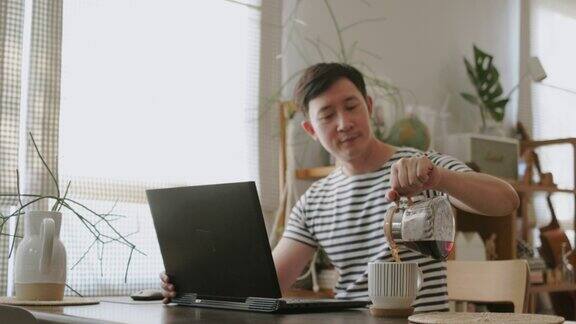 亚洲男人在家里工作往杯子里倒热的美式咖啡