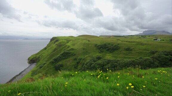 在苏格兰斯凯岛的海边悬崖上有绿色的草地和山脉