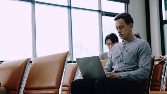 亚洲商人使用笔记本电脑在机场候机大厅开会等待登机在终端提供互联网服务亲自入住