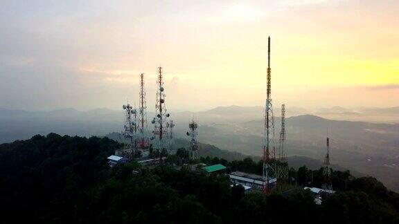 城市上空的山上日出时电信天线的鸟瞰图
