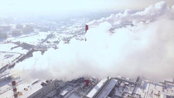 从飞行的无人机看到的烟雾从锅炉管道在城市供暖现代城市鸟瞰图中发电厂冒烟的烟囱工业管道排放的烟雾