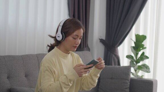 女人戴着耳机听着音乐开心地在家里度假在客厅的沙发上开心地躺着