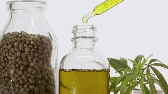 滴管将油滴入大麻枝附近的瓶子和盛有种子的罐子