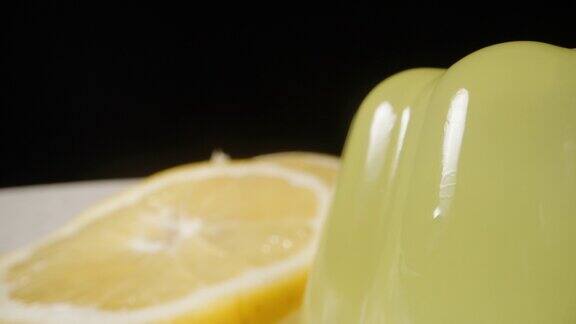 柠檬片和黄色果冻放在白色盘子里黑色背景多莉滑块极端特写
