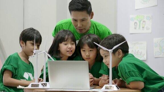 在小学课堂上信息生态教师使用笔记本电脑给小学生上关于废物回收的课