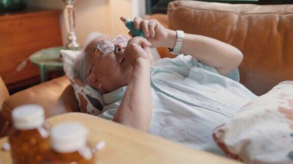 老人在家里的沙发上使用哮喘吸入器