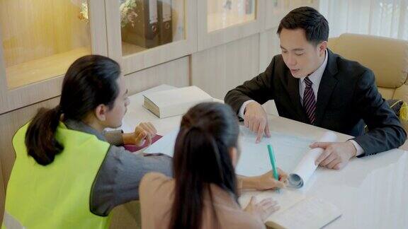 三个人一对亚洲夫妇和股票市场的高级专业财务顾问在办公室里谈话桌子上放着很多文件漂亮的女孩用左手写重要的信息