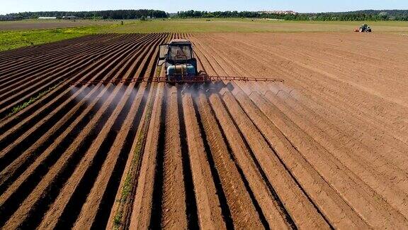 农民在拖拉机上向犁过的田地喷洒化肥和化学药品