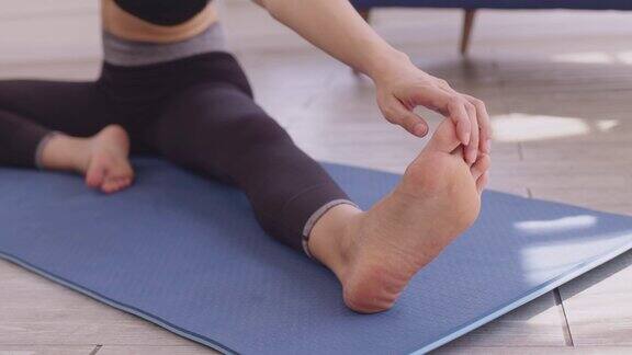 妇女在瑜伽垫上做伸展手臂和腿部肌肉的运动