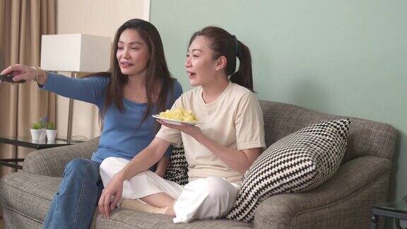 千禧一代的亚洲女性朋友们一起在家里的客厅里看电视