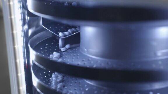 生产药丸、片剂的过程工业制药概念工厂设备和机器许多药丸在机器上移动医疗胶囊是用传送带分类的