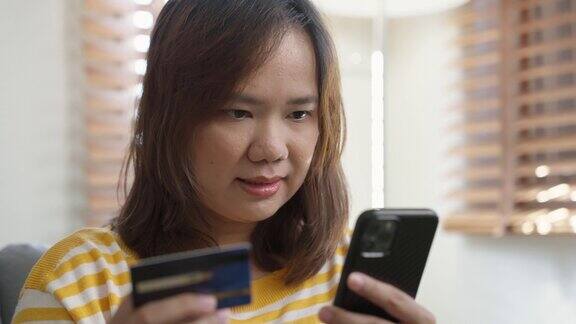 一名亚洲妇女用手机用信用卡网购