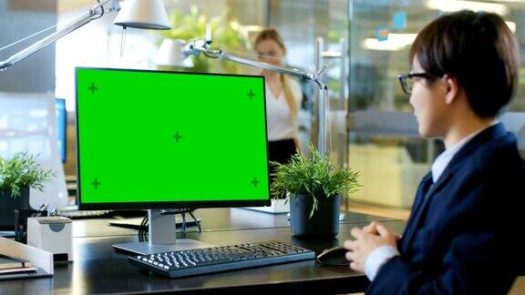 在办公室商人在模拟绿色屏幕的个人电脑上进行视频通话