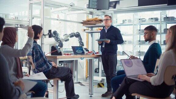 大学机器人课:教师用机械臂向学生讲解工程学编程机械手的年轻工程师团队计算机科学教育构建、设计、学习