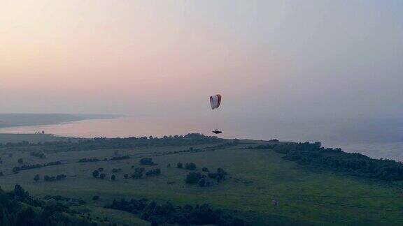在夕阳背景下运动员在空中的滑翔伞上飞行滑翔伞动作极限运动概念