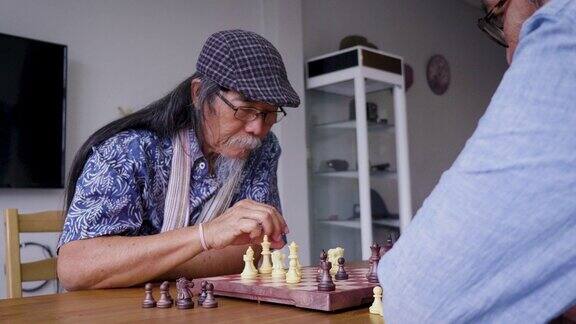 亚洲资深男士朋友在家里客厅下棋积极的资深人士理念