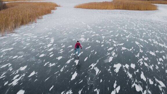鸟瞰图一个年轻女子在结冰的湖面上滑冰