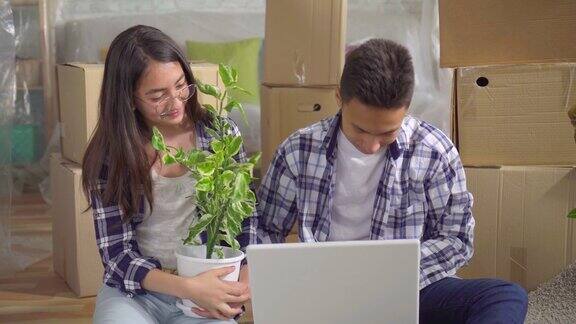 一对年轻的亚洲夫妇搬进了一个新公寓他们坐在地板上使用笔记本电脑