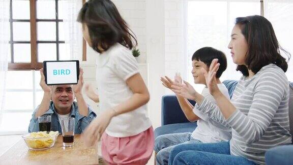 快乐快乐的亚洲家庭在家里客厅的沙发沙发上玩着数码平板电脑玩游戏的爱好