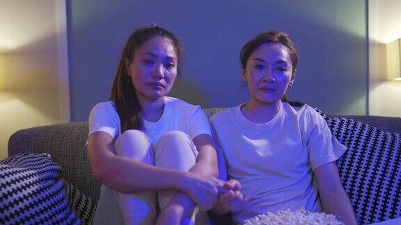 4K千禧一代的亚洲女性朋友一起在家里的客厅里看电视