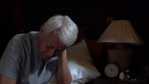 坐在床上的抑郁的老年人因失眠而无法入睡