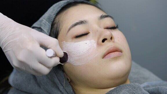 4K美容师在亚洲女性脸上涂抹护理面膜