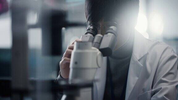 医学发展实验室:东亚科学家在显微镜下观察的肖像分析培养皿样本大型制药实验室从事医学、生物技术、微生物学、药物研究