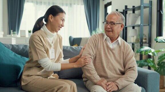 年轻的亚洲女性专业护理人员照顾老男人分享一个故事一起在家里的客厅