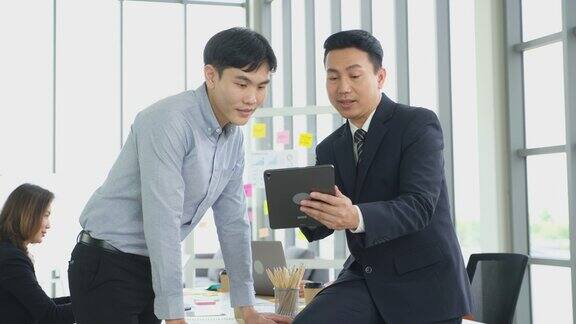 亚洲商务人士在办公室开会进行头脑风暴亚洲经理手持平板电脑向同事展示工作计划项目成功的商业理念团队战略