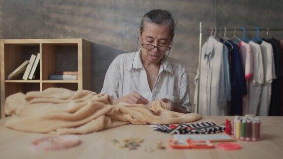 退休亚洲妇女缝纫她的衣服手工