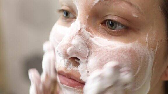 一位年轻女子正在洗脸用泡沫洗面奶洗脸日常面部护肤程序