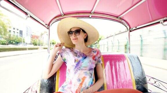 年轻漂亮的女游客戴着帽子在泰国曼谷乘坐传统的泰国巴士songteo