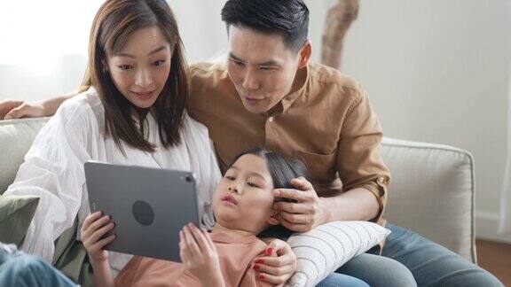 幸福的家庭在客厅的沙发上使用数码平板电脑作为媒体