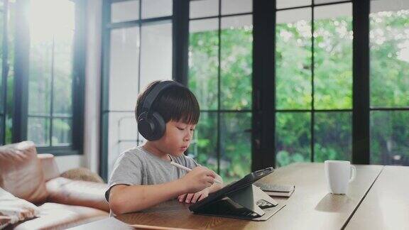 亚洲年轻男孩使用数字平板电脑学习在家通过在线学校老师的教学家庭学校的孩子使用手写笔书写或绘制在显示设备上的在线课堂学校