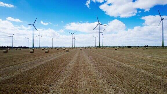 上图一排风力涡轮机优雅地在林肯郡一个农民的田里转动田里刚刚收获了庄稼前面是金色的干草捆