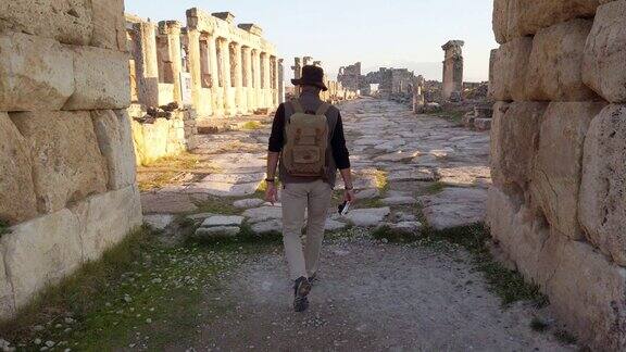 一名摄影游客正在向位于棉花堡希拉波利斯的古遗址中的Frontinus门走去