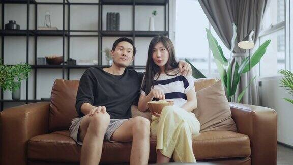 亚洲成人恋人结婚夫妇享受在沙发沙发上看电视一起在家里享受宁静和幸福居家隔离的生活方式