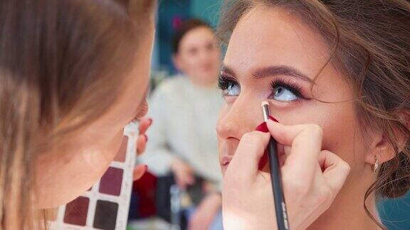 化妆师用画笔画一个美丽女孩的眼睑特写
