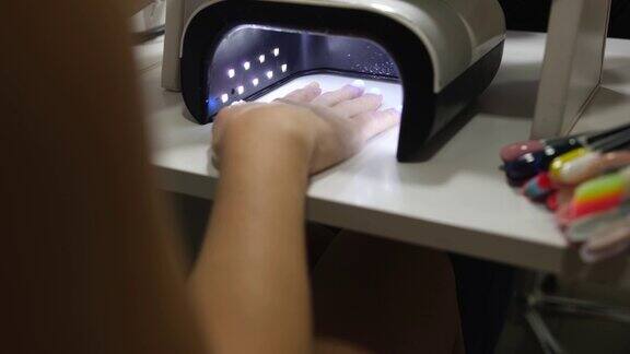 女客户用紫外线灯近距离4k电影在指甲上晒指甲油