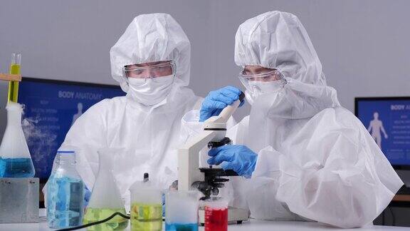 身穿个人防护装备的科学家团队正在实验室的试管中做一些研究检查一种液体