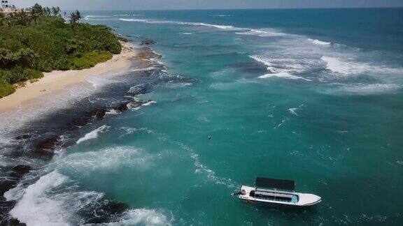 无人机俯瞰异国情调的度假海滩小船热带树木泡沫的海浪撞击美丽的海岸