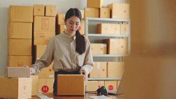 亚洲妇女在网上商店仓库工作包装产品到包裹纸箱网上电子商务零售的小商业概念