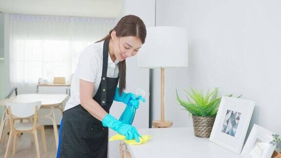亚洲清洁服务女工清洁客厅在家里美丽的女孩家庭主妇管家清洁工感到高兴擦凌乱肮脏的工作桌上的家务或家务