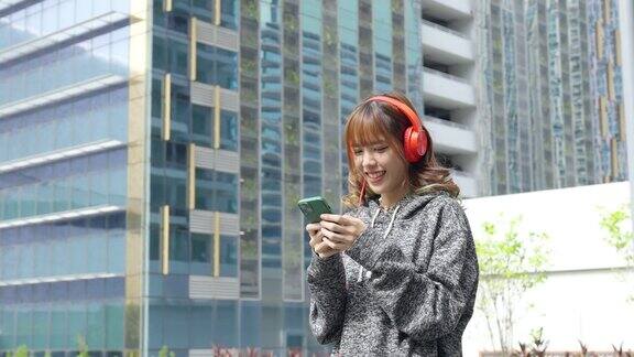 4K亚洲女性在城市里戴着耳机用手机听音乐